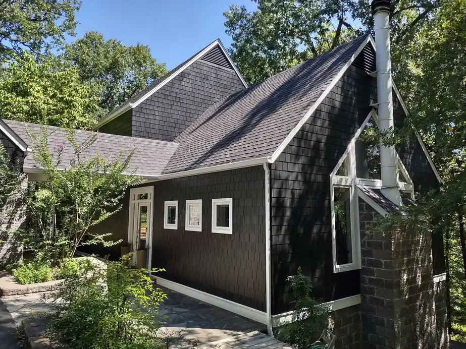 A dark shake-sided cabin with white trim