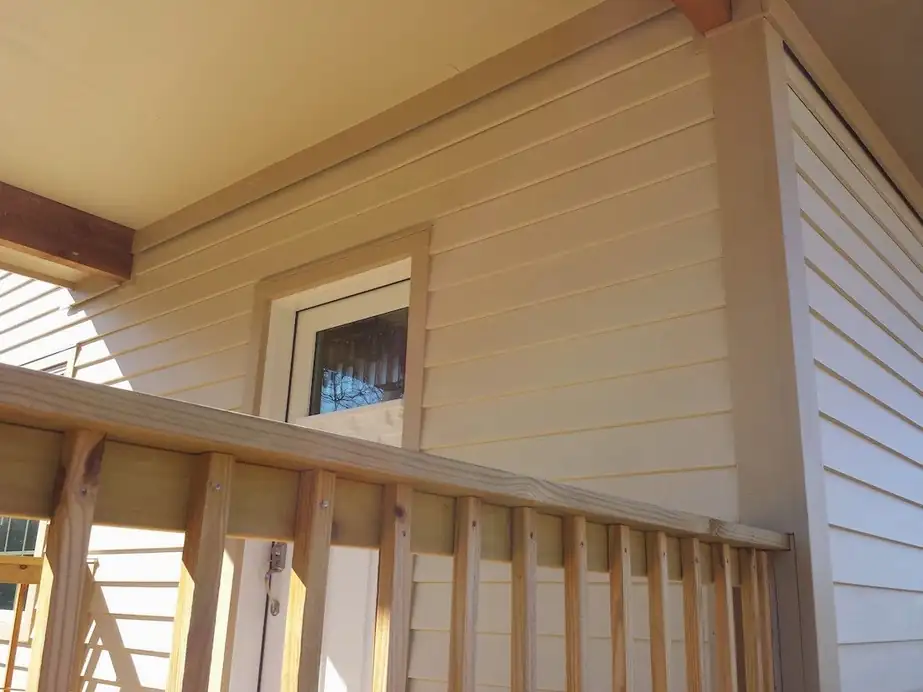 A porch soffit above lap siding with tan trim