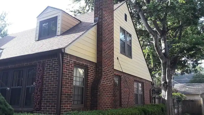 The same brick house with a yellow siding gable beside a brick chimney