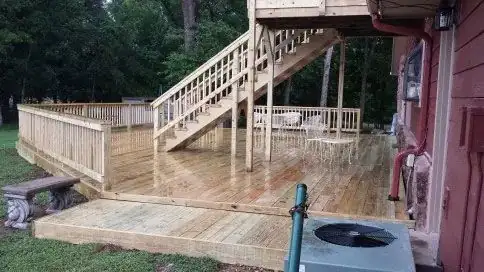 A new wooden deck with a set of stairs beside a red house