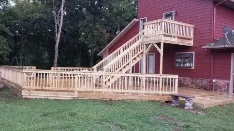 A deck and its stairs seen from the side of a red house