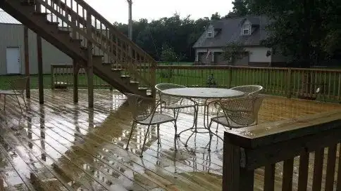 A wet wooden deck with a patio table